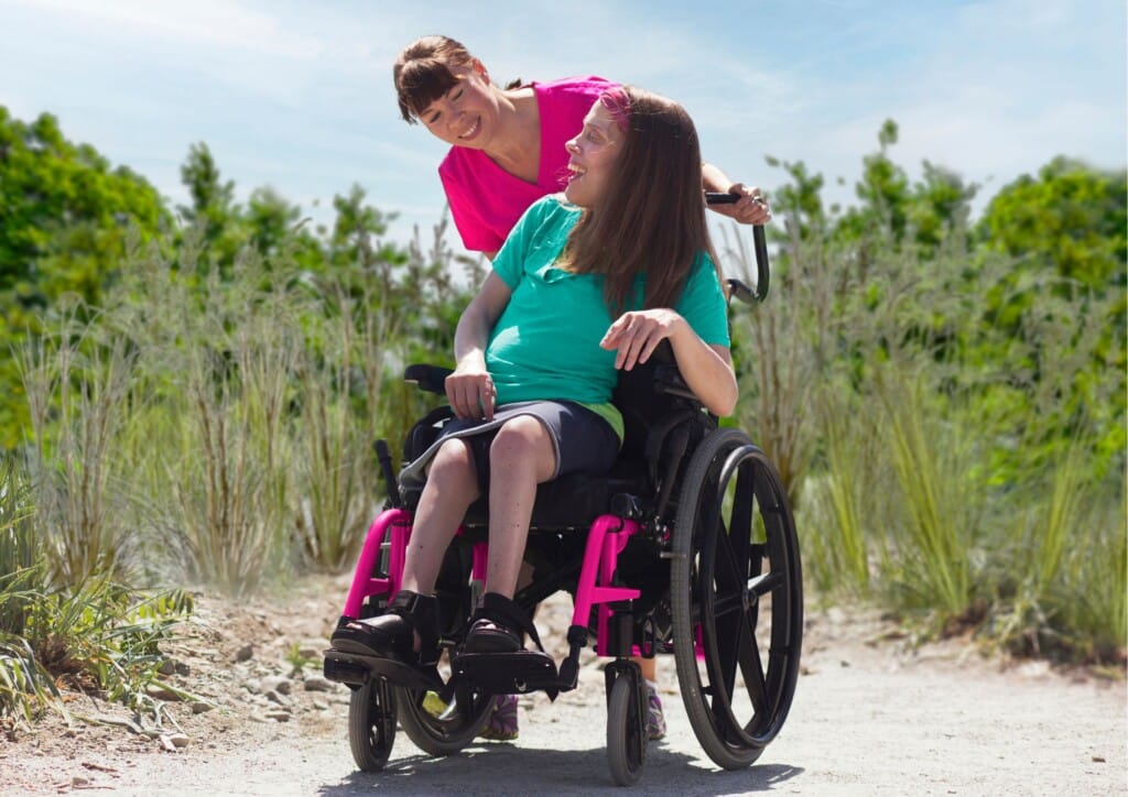 Caregiver and client with Disability smiling at each other outdoors