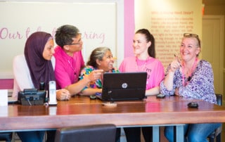A Nurse Next Door home care franchise owner chats with staff at the front desk of the business